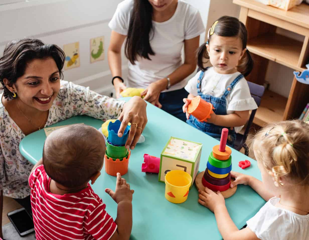 Children playing with colorful stacking toys in a preschool classroom.