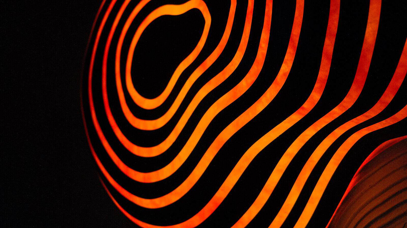 Glowing, orange lines swirl against a black background.