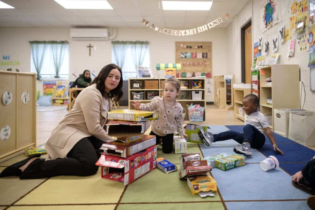 Childcare classroom with teacher and children playing with educational toys and books.
