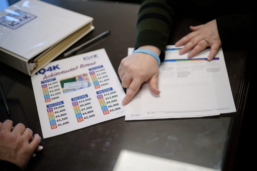 Person reviewing financial documents and achievement bonus chart at desk.