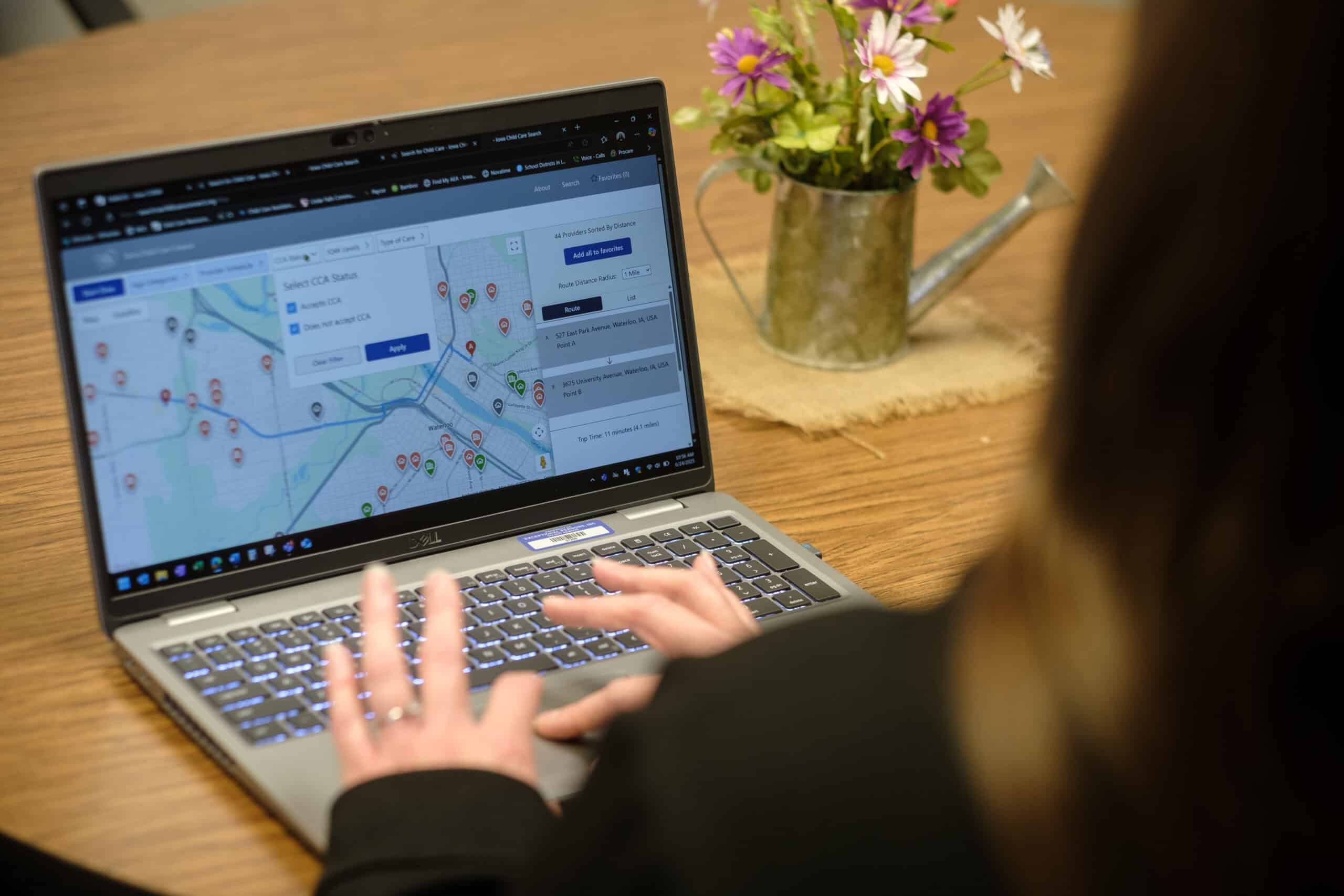 Person using a laptop to view Iowa Childcare Resource & Referral map and contact info.