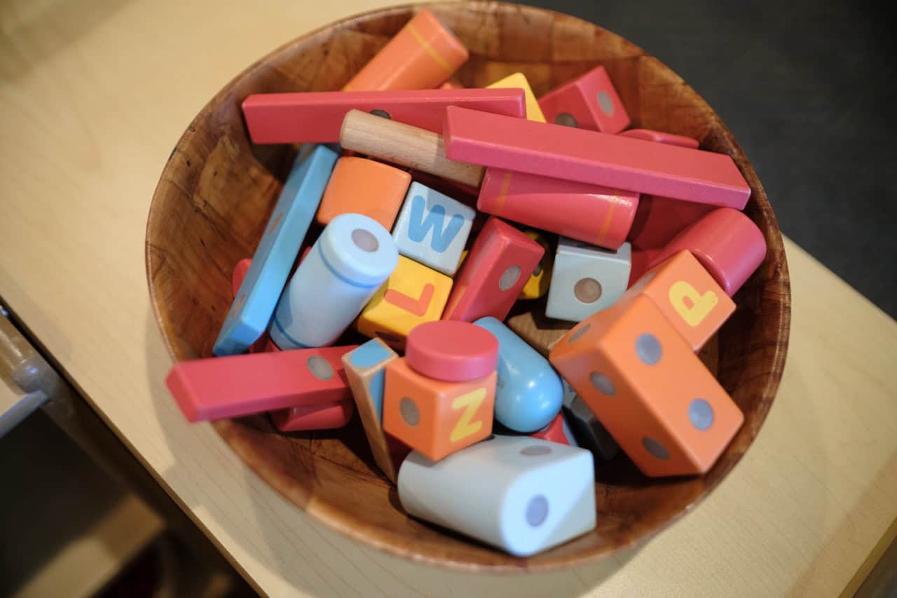 Colorful children's building blocks in a wooden bowl for early childhood education.