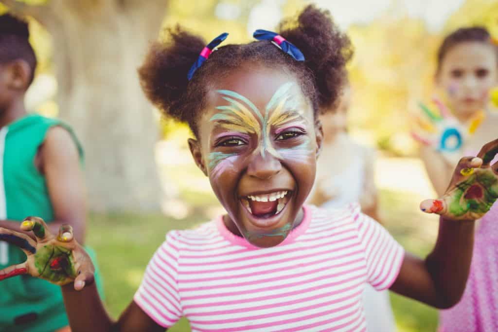Child with face paint smiling outdoors during a childcare event in Iowa.