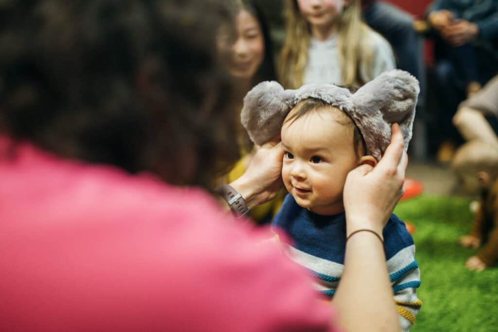 Childcare provider gently adjusts a child's bear hat at Iowa Childcare Resource & Referral event.