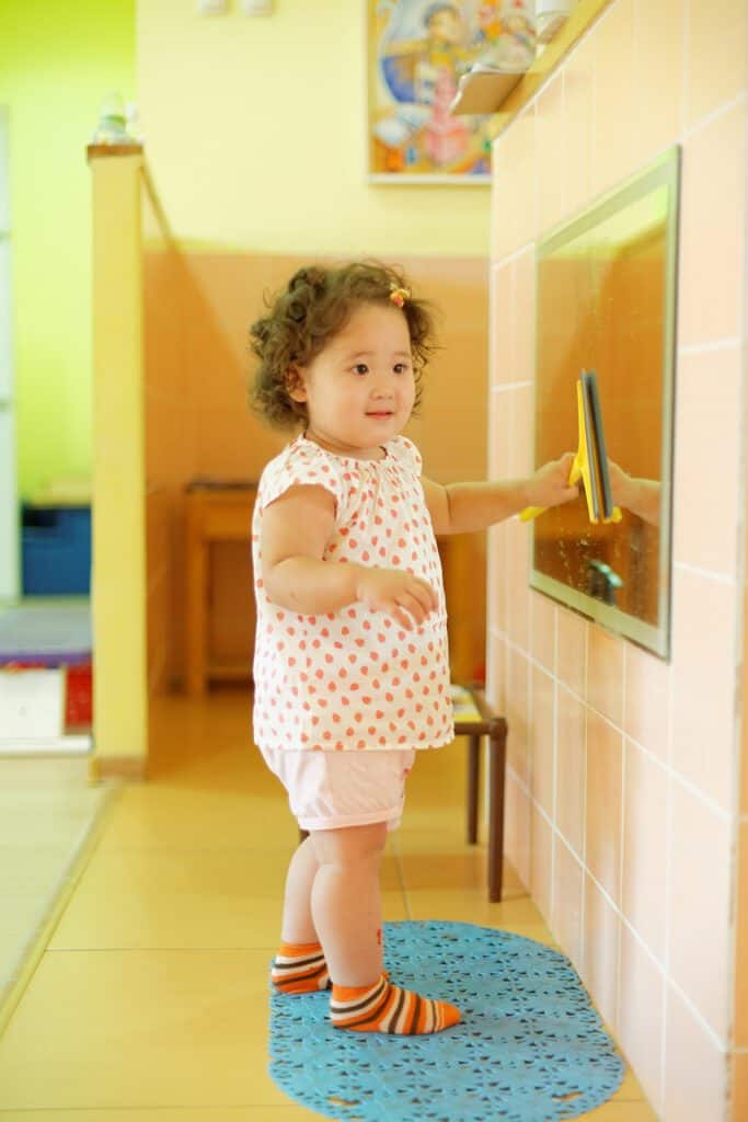 Young girl using an interactive touchscreen in a colorful childcare setting.