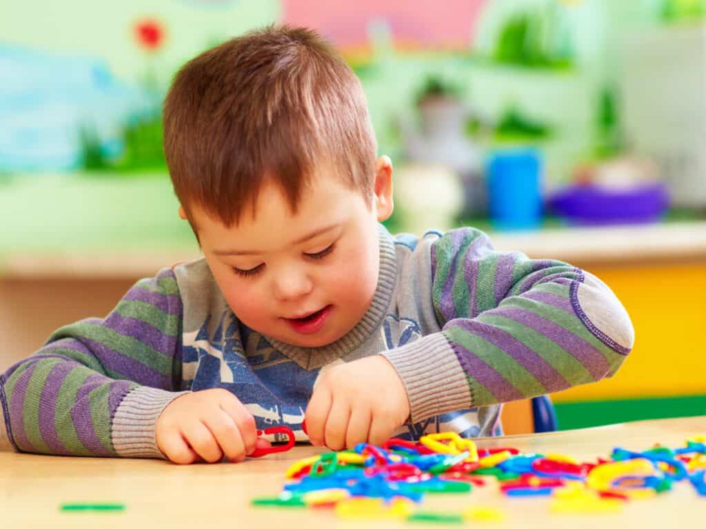 Young boy playing with colorful educational toys in a bright classroom.