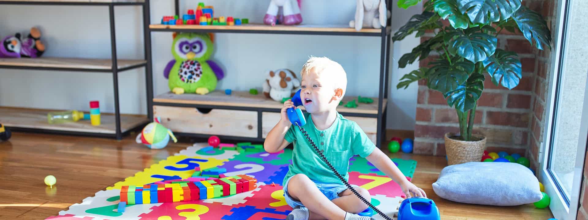 Young child playing with toys in a colorful indoor playroom.