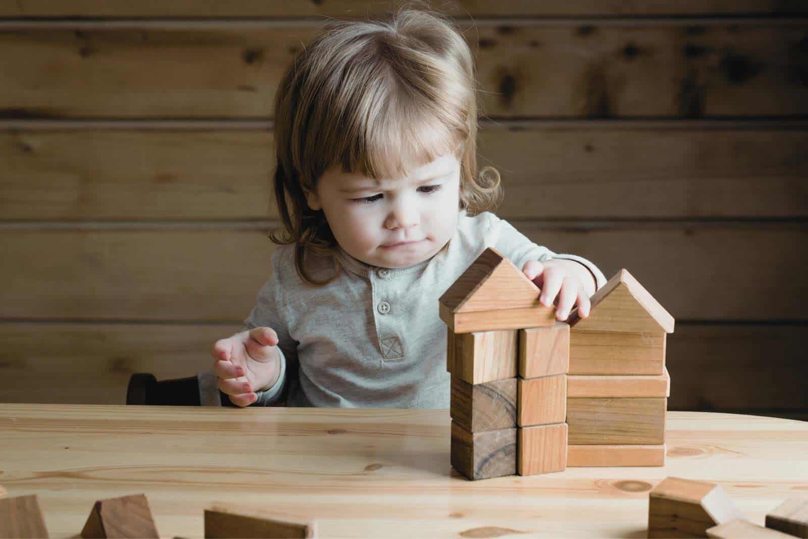 Young girl building a house with wooden blocks at a child care center.