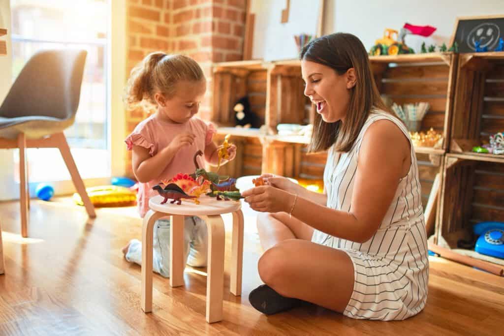 Young woman playing with a child in a cozy, well-lit childcare home setting.