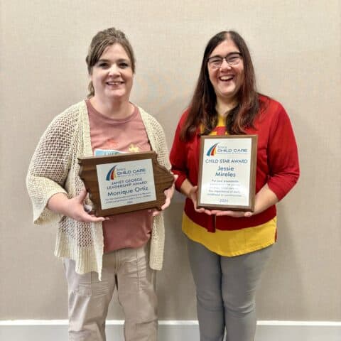 Two women holding awards at Iowa Childcare Resource & Referral event.